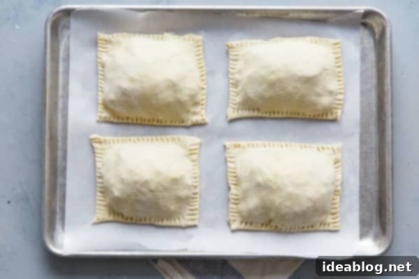 Golden Potato Leek Cornish Pasty 4 Unbaked potato leek pasties on a sheet pan, brushed with egg wash and ready for the oven