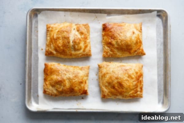 Golden Potato Leek Cornish Pasty 5 Freshly baked Potato Leek Cornish Pasties on a sheet pan, showcasing golden brown crusts