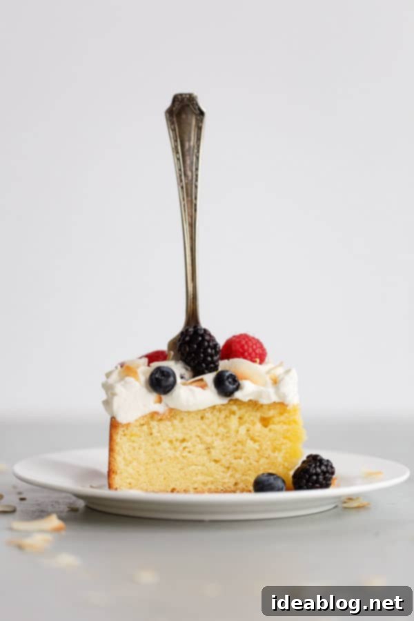A beautiful cross-section of Lemon Coconut Cake, perfectly frosted with whipped cream and adorned with fresh berries, promising a delightful dessert experience. #cakeslice #lemonsummercake #coconutflavour #berriesandcream Slice of Lemon Coconut Cake with Whipped Cream Frosting and Berries