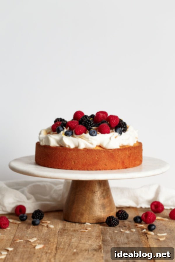 Close-up of the stunning Lemon Coconut Cake, highlighting its elegant presentation with whipped cream, fresh mixed berries, and a sprinkle of lemon zest and toasted coconut. #celebrationcake #homemadedessert #bakinglove #lemonrecipe Lemon Coconut Cake with Whipped Cream and Berries