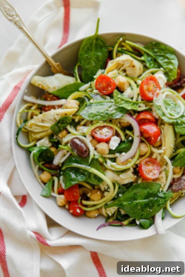 Mediterranean Zucchini Pasta Salad - this refreshing and lightened up Mediterranean Zucchini Pasta Salad is prepared with zucchini noodles in lieu of traditional pasta, and tossed with briny feta, chickpeas, artichoke hearts, tomatoes, spinach, and olives. #zucchini #vegetarian #glutenfree #abeautifulplate #healthy #Mediterranean Mediterranean Zucchini Pasta Salad