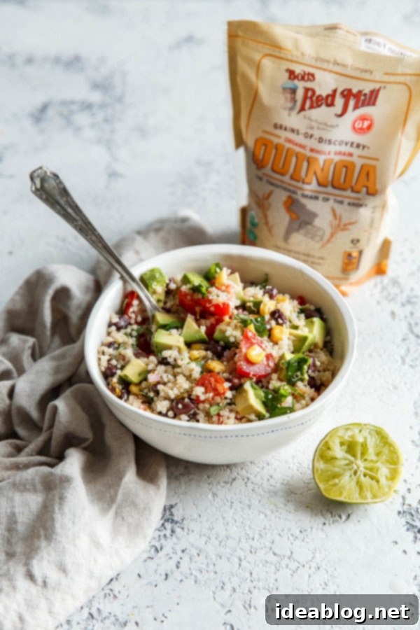 Southwest Quinoa Salad - an easy, flavorful, and vegetarian southwestern quinoa salad with black beans, tomatoes, jalapeño, red onion, cotija cheese, fire roasted corn, and a simple lime vinaigrette. #salad #quinoa #abeautifulplate #healthy #summer #recipe Overhead view of a large bowl of Southwest Quinoa Salad with fresh lime slices