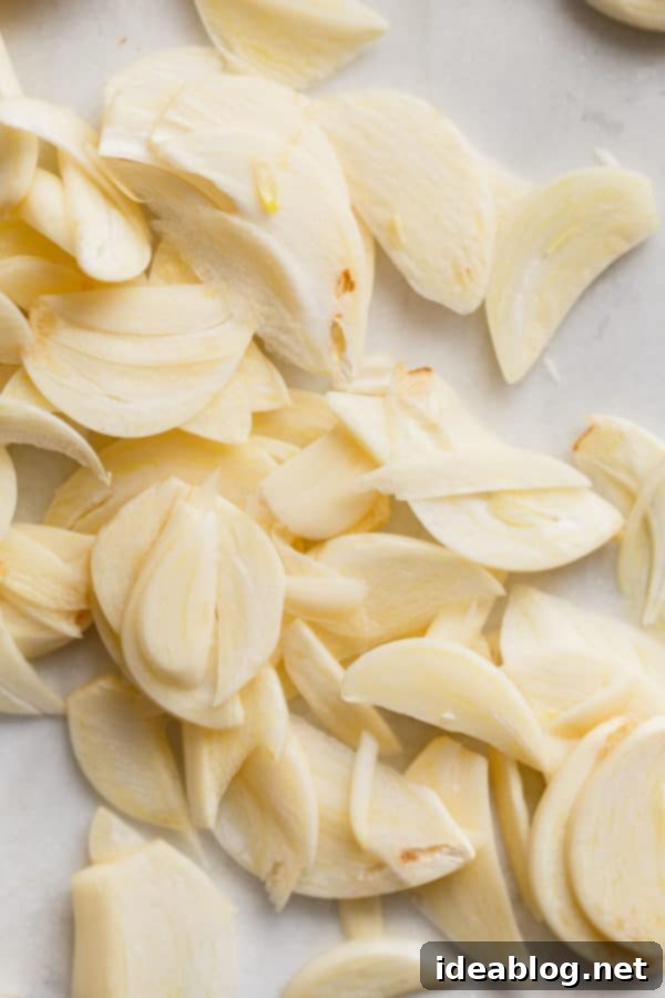 How to Make Crispy Garlic Chips - An easy, no-fuss tutorial on how to make crispy garlic chips at home, and ways to incorporate them into your cooking repertoire.  A close-up view of raw, thinly sliced garlic cloves, glistening and ready to be transformed into crispy chips.