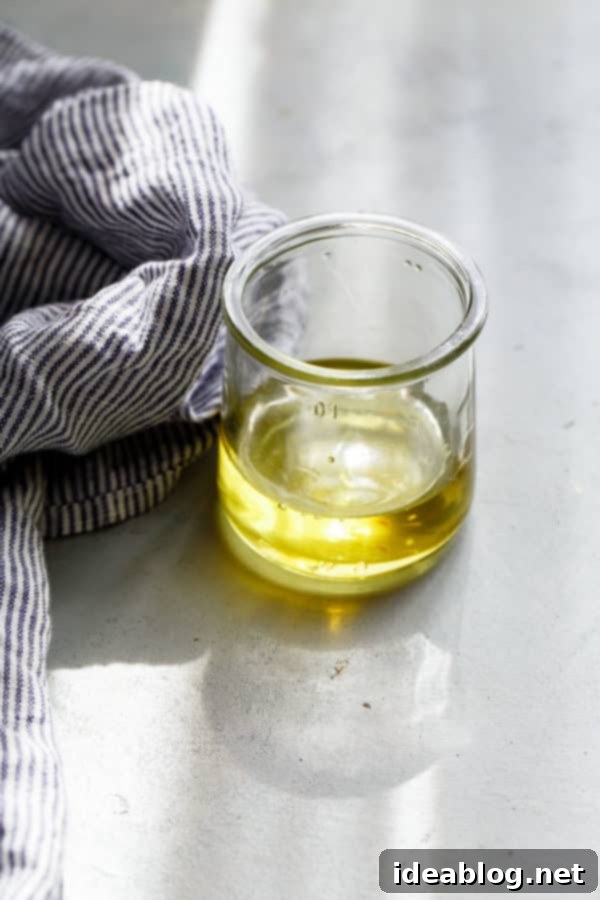 How to Make Crispy Garlic Chips - An easy, no-fuss tutorial on how to make crispy garlic chips at home, and ways to incorporate them into your cooking repertoire.  A small glass bottle filled with golden garlic-infused oil, showcasing the rich color and clarity of the byproduct.
