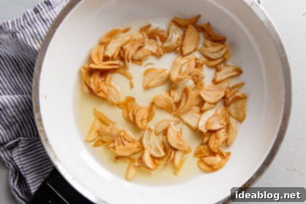Crispy Homemade Garlic Chips 4 Garlic chips being stirred in a skillet, illustrating the continuous movement required for even cooking and perfect crispness.