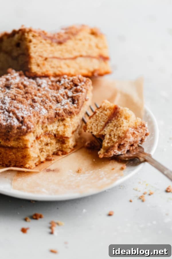 Spiced Coffee Cake with Pumpkin Butter Swirl - this AMAZING coffee cake recipe is infused with warm fall spices and filled with an incredible pumpkin butter layer. Perfect for holiday entertaining, breakfast, or brunch! A delectable slice of Spiced Coffee Cake with Pumpkin Butter on a plate, accompanied by a fork, ready to be enjoyed.