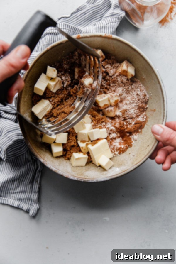 Harvest Spice Coffee Cake with Creamy Pumpkin Swirl 6 Ingredients for coffee cake streusel topping in a bowl, including flour, brown sugar, and spices, with a pastry cutter.