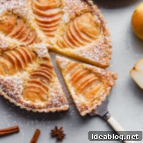 Elegant Pear & Almond Tart 10 A stunning Pear Frangipane Tart with a slice cut out, ready to serve for a delightful dessert experience