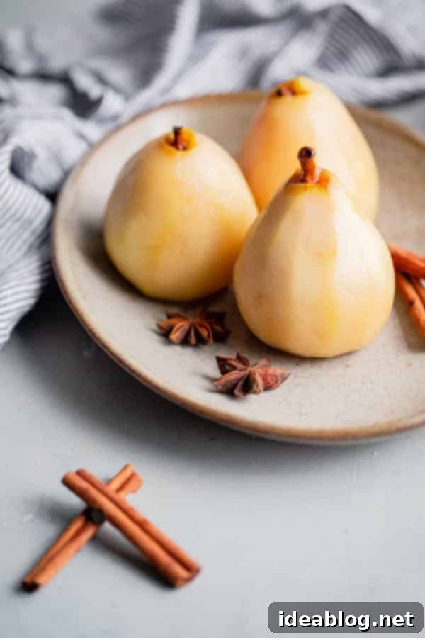 Pear Frangipane Tart - this classic French poached pear tart recipe is made with a sweet tart dough and filled with poached pears and frangipane (almond cream). This tart is delicious and is wonderful served on Thanksgiving or over the holiday season! Top with powdered sugar or apricot glaze. #tart #recipe #pear #frangipane #poached #French #dessert #pastry Exquisitely poached pears resting on a platter, glistening with syrup and ready to be incorporated into the French Frangipane Tart, showcasing their firm yet tender texture and aromatic infusion