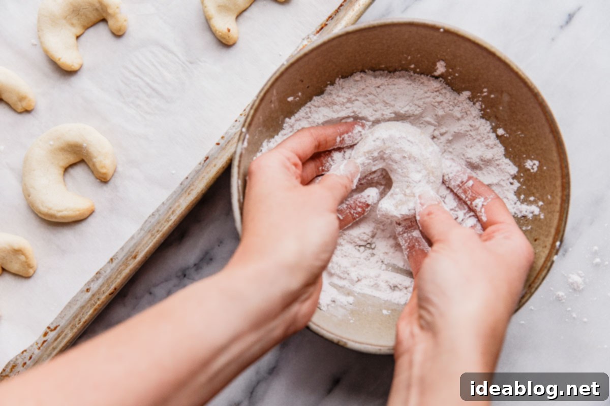 Buttery Almond Moons 15 Dusting baked almond crescent cookies with powdered sugar using a sieve.
