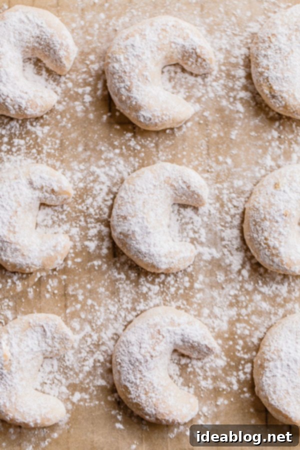 Buttery Almond Moons 3 Close-up of baked almond crescent cookies, with a hint of golden brown on the edges.
