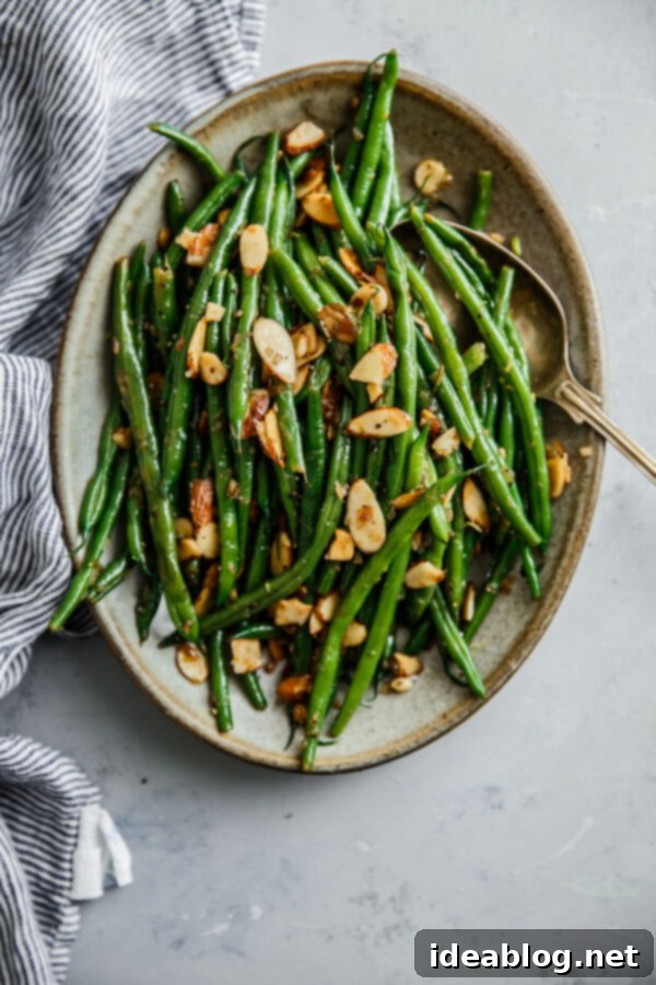 Elevated Green Beans Almondine: A Classic French Side Dish for the Holidays Green Beans Almondine - a classic French recipe of green beans with almonds, elevated with sautéed shallots, garlic, lemon zest, and lemon juice. An elegant, simple, and delicious side dish, perfect for holidays and can be prepped ahead. #vegetables #sidedish #recipe #greenbeans #almonds #lemon #vegetarian #glutenfree