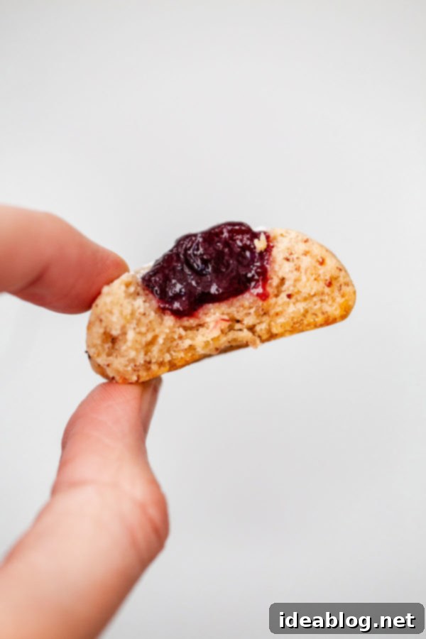 Buttery hazelnut thumbprint cookies filled with a soft berry jam center. These little cookies are easy to make, flavorful, and a lovely last-minute addition to your holiday table! #thumbprint #cookie #christmas #berry #recipe #abeautifulplate Hazelnut Thumbprint Cookies with Vibrant Jam Filling