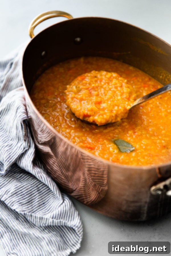 Healthy, hearty, and delicious Red Lentil Soup made with simple ingredients like onions, leeks, carrots, celery, crushed canned tomatoes, and red split lentils. Naturally gluten free, this delicious soup recipe will become a staple in your kitchen! #abeautifulplate #glutenfree #lentils #healthy #soups via @abeautifulplate Hearty Red Lentil Soup simmering gently in a rustic copper pot, emitting warmth and delicious aromas.