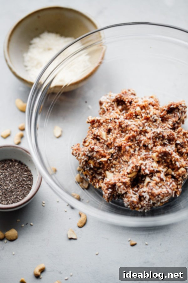 Coconut Cashew Chia Power Bites 3 The blended mixture for energy bites in a food processor bowl, showing a thick, sticky consistency before adding chunky ingredients.