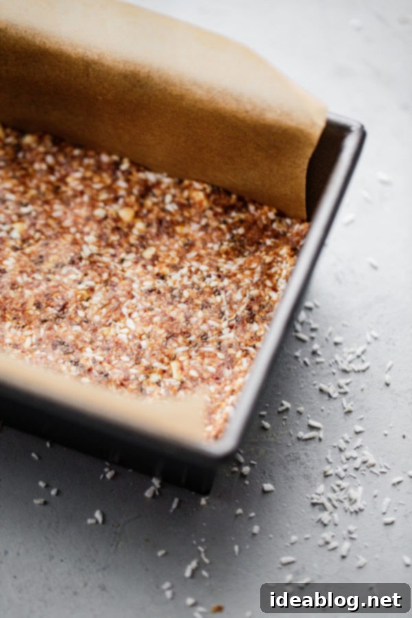 The no-bake energy bite mixture pressed firmly into a parchment-lined loaf pan, ready for chilling.