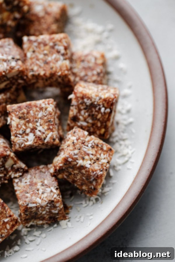 Coconut Cashew Chia Energy Bites - a super satisfying, naturally sweetened snack packed with dates, cashews, coconut, chia, sesame, and orange zest. Gluten-free, paleo, and vegan friendly. A close-up shot of a single Coconut Cashew Chia Energy Bite, highlighting its varied texture from dates, cashews, coconut, and seeds.