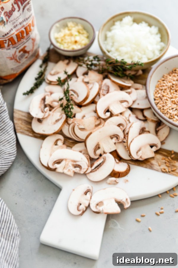 Simple Savory Mushroom Farro Risotto 3 Freshly sliced cremini (baby bella) mushrooms on a wooden cutting board, ready for cooking.