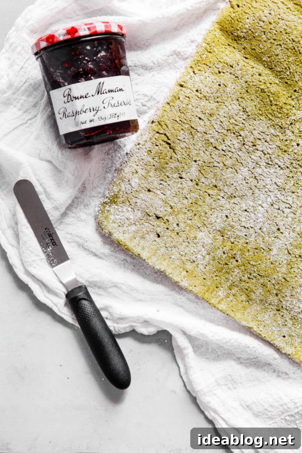 Vibrant Raspberry Matcha Roll Cake 5 Matcha Roll Cake batter spread on a baking sheet, ready for rolling