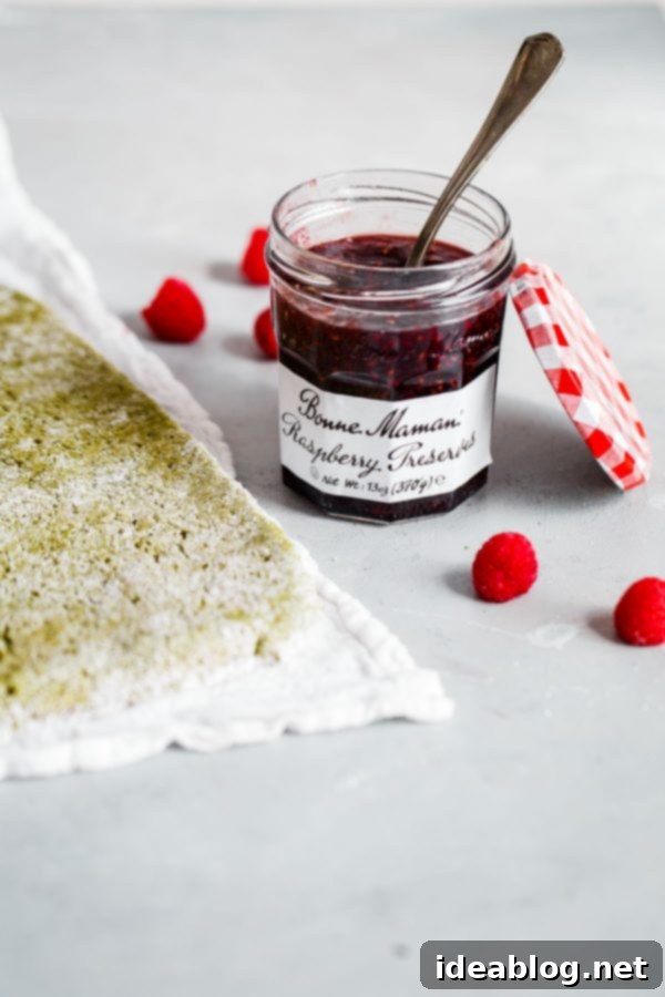 Raspberry Matcha Roll Cake - a visually stunning Swiss roll featuring earthy matcha and sweet-tart Bonne Maman Raspberry Preserves, ideal for spring celebrations. #matcha #raspberry #swissroll #bonnemaman Matcha Roll Cake filled with Bonne Maman Raspberry Preserves and raspberry cream