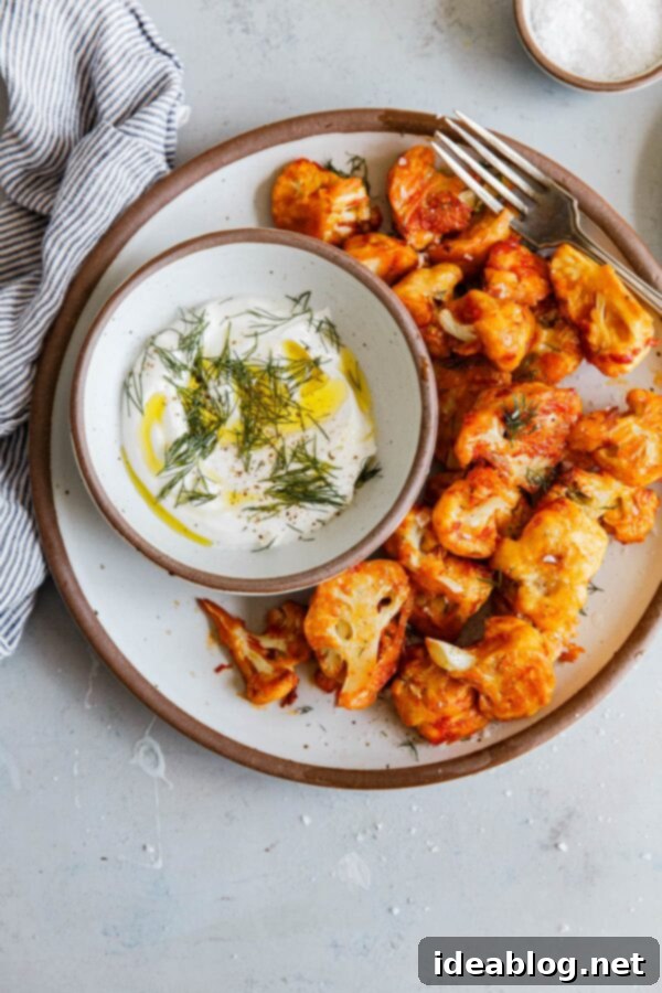 Easy Buffalo Cauliflower - these buffalo cauliflower bites are made with fresh cauliflower florets, tossed in a buttermilk flour mixture, and roasted at a hot temperature until crisp. A delicious and vegetarian twist on classic buffalo chicken! Serve with yogurt sauce or blue cheese dip.  #abeautifulplate #buffalo #cauliflower #recipe #vegetarian #baked #healthy #skinny #easyrecipes Baked Buffalo Cauliflower Bites with Yogurt Dipping Sauce