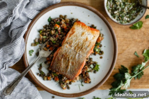 Pan Seared Salmon with Lentils - crispy pan seared salmon topped with a zesty caper herb vinaigrette and served alongside a flavorful French lentil salad. #sponsored #salmon #lentils #abeautifulplate #recipe #healthy #dinner #glutenfree #dairyfree Pan Seared Salmon with Lentils - a close-up of the perfectly cooked salmon fillet, ready to be served.
