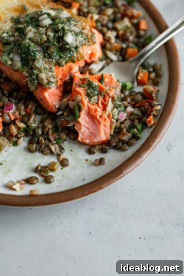 Pan Seared Salmon with Lentils, topped with fresh herbs and seasoning.