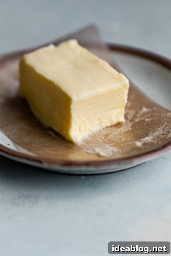 The Art of Cultured Butter 8 A hand shaping a block of homemade cultured butter on wax paper, preparing it for storage.