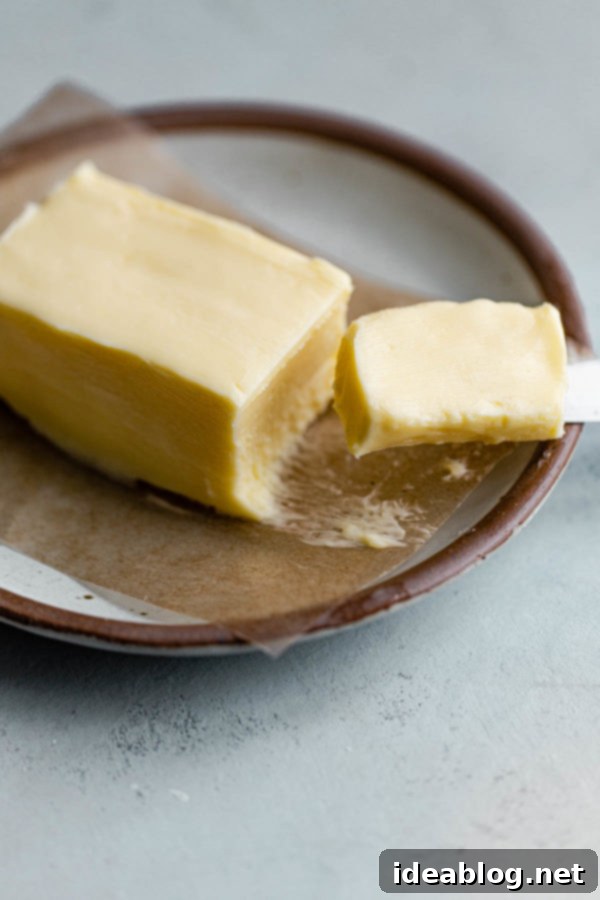 Serving Suggestion: Homemade Cultured Butter on Sourdough Bread A block of homemade cultured butter artfully spread on a slice of fresh sourdough bread, garnished with a sprig of fresh thyme.