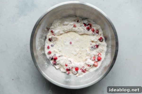 Sunrise Cranberry Orange Scones 6 Shaggy dough for cranberry scones being mixed in a bowl with heavy cream.