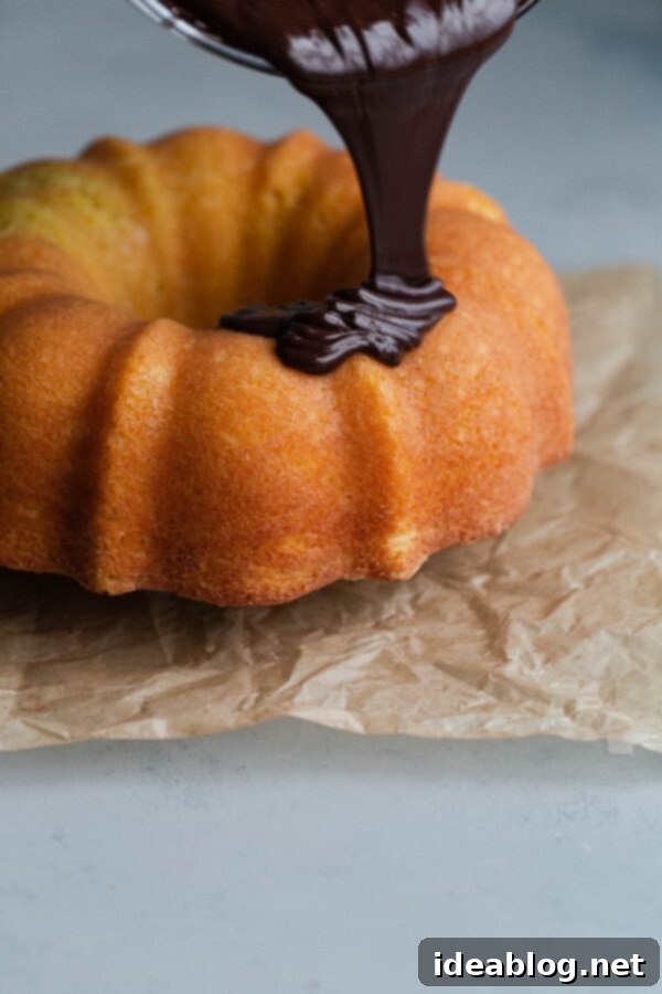 Zesty Orange Bundt with Chocolate Drizzle 5 Chocolate Glaze Being Poured on Orange Bundt Cake - Decadent dark chocolate ganache drizzling over a freshly baked orange bundt cake.