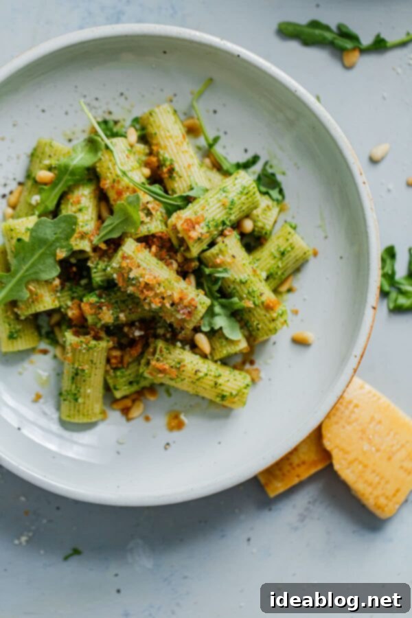 EASY Arugula Pesto Pasta - an easy twist on basil pesto made with baby arugula! Bright, peppery in flavor, and affordable to make, this arugula pesto pasta is a year-round favorite. #pasta #easydinner #recipe #abeautifulplate #arugula #pesto Arugula Pesto Pasta with Crispy Garlicky Breadcrumbs on a rustic plate