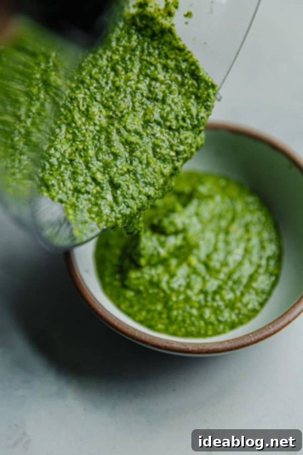 Vibrant Arugula Pesto Pasta with Golden Garlic Crumble 5 Freshly made Arugula Pesto being poured into a bowl
