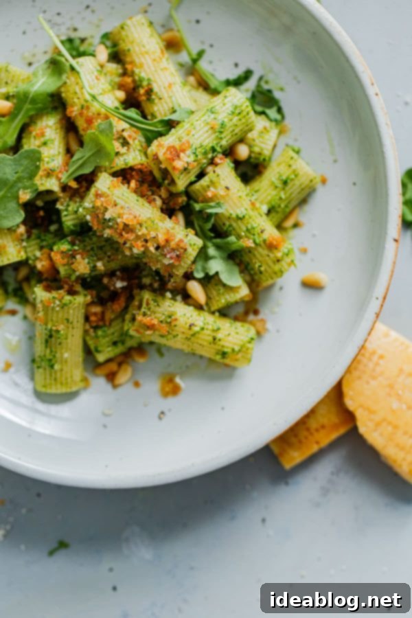 EASY Arugula Pesto Pasta - an easy twist on basil pesto made with baby arugula! Bright, peppery in flavor, and affordable to make, this arugula pesto pasta is a year-round favorite. #pasta #easydinner #recipe #abeautifulplate #arugula #pesto Arugula Pesto Pasta served on a white plate with a fork