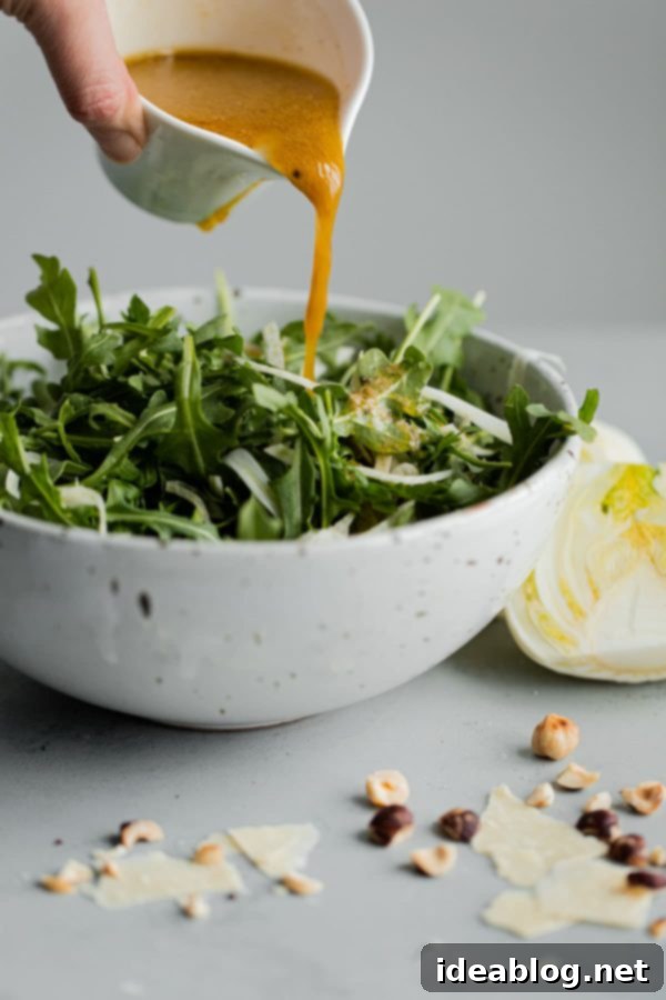 Shaved Fennel Arugula Salad with Hazelnuts, Parmesan, and Sherry Vinaigrette. A simple salad to enjoy year round. Great for everyday meals or special occasions! #abeautifulplate #salad #arugula #hazelnuts #parmesan #recipe  Sherry Vinaigrette Being Poured on Salad