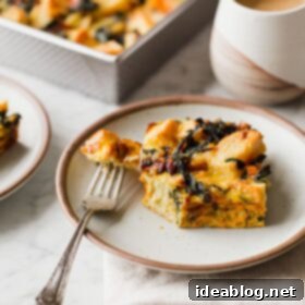 Overnight Vegetarian Breakfast Bake 6 A delicious slice of Overnight Vegetarian Breakfast Strata on a white plate, garnished with fresh herbs.