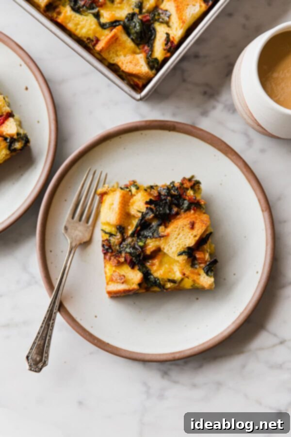 Overnight Breakfast Strata - cheesy, pillowy, and deeply satisfying, this vegetarian breakfast casserole is wonderful any time of year, but particularly ideal for holiday entertaining. #holiday #entertaining #recipe #abeautifulplate #eggs #casserole #chard #cheese #easyrecipes #vegetarian Close-up view of a baked Swiss Chard and Cheese Strata slice on a plate, showcasing its fluffy texture and golden crust.