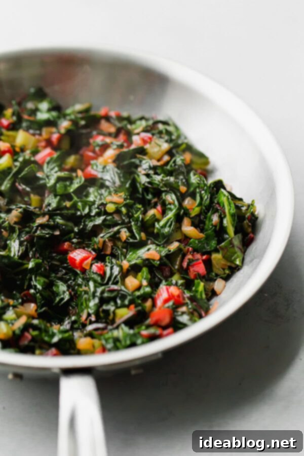 Overnight Vegetarian Breakfast Bake 2 Swiss chard stems and leaves being sautéed in a skillet, turning vibrant green and tender.