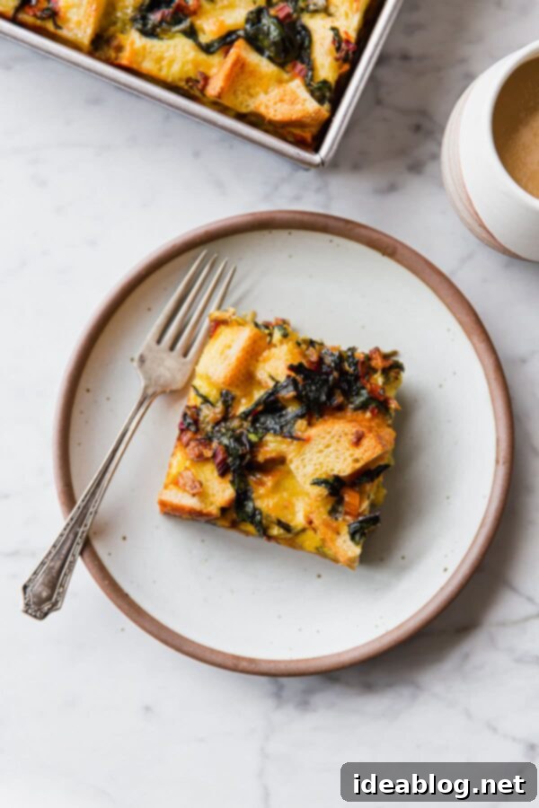 Overnight Vegetarian Breakfast Bake 5 A serving of Swiss Chard and Cheese Strata on a white plate, garnished with a sprig of fresh parsley.