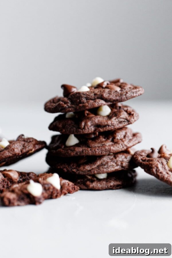 Triple Chocolate Cookies - Chewy triple chocolate cookies featuring semisweet, milk, and white chocolate chips. This chocolate cookie recipe is a chocolate lover's dream. #recipe #cookies #chocolate #abeautifulplate #desserts Stacked Triple Chocolate Cookies showcasing a beautiful array of white, milk, and dark chocolate chips