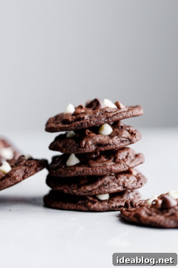 Triple Chocolate Cookies - Chewy triple chocolate cookies featuring semisweet, milk, and white chocolate chips. This chocolate cookie recipe is a chocolate lover's dream. #recipe #cookies #chocolate #abeautifulplate #desserts A stack of perfectly baked triple chocolate cookies, highlighting their crisp edges and generous chocolate chips