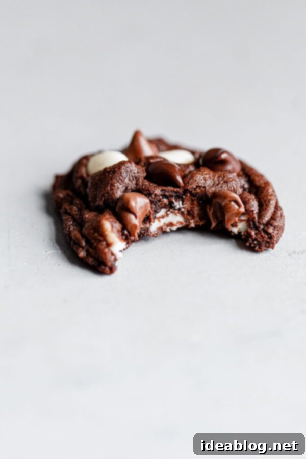 Decadent Triple Chip Chocolate Cookies 3 A perfectly baked, slightly chewy chocolate cookie with a bite taken out, revealing melted chocolate chunks