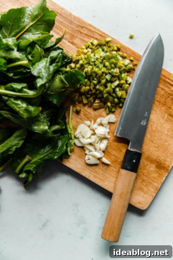 How to Cook Beet Greens - this simple sautéed beet greens recipe calls for just extra virgin olive oil, fresh garlic, red pepper flakes, and lemon zest to produce hearty, healthy greens. #abeautifulplate #beets #vegetarian #vegan #glutenfree #dairyfree #abeautifulplate #howto Chopped Beet Greens with Garlic on Cutting Board