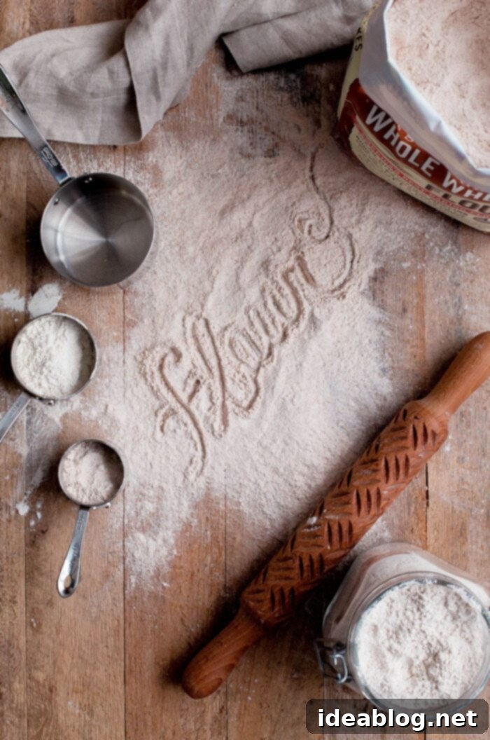 Sourdough Starter Rescue 2 Assorted flour types dusted on a wooden board with measuring cups, essential for sourdough baking.