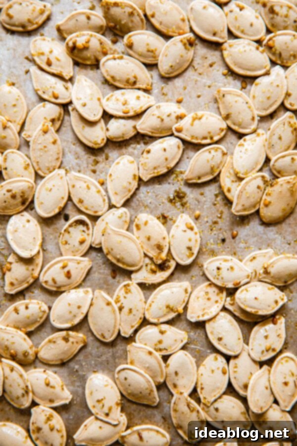 Savory Za'atar Roasted Pumpkin Seeds 2 Pumpkin Seeds Tossed with Za'atar Seasoning on a baking sheet, showcasing the beautiful coating.