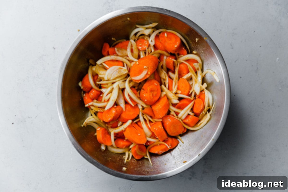 Roasted Golden Carrots with Savory Farro 13 Sliced Carrots and Onions in Stainless Steel Bowl, perfectly seasoned and ready to be roasted.