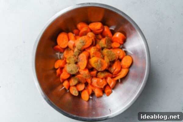 Roasted Golden Carrots with Savory Farro 5 Sliced Carrots ready to be seasoned with Cumin and other spices in a stainless steel bowl.