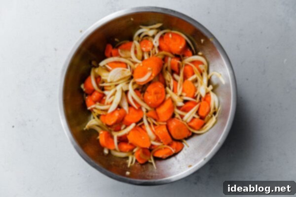 Roasted Golden Carrots with Savory Farro 6 Sliced Carrots and Onions mixed together in a large stainless steel bowl, prior to seasoning.