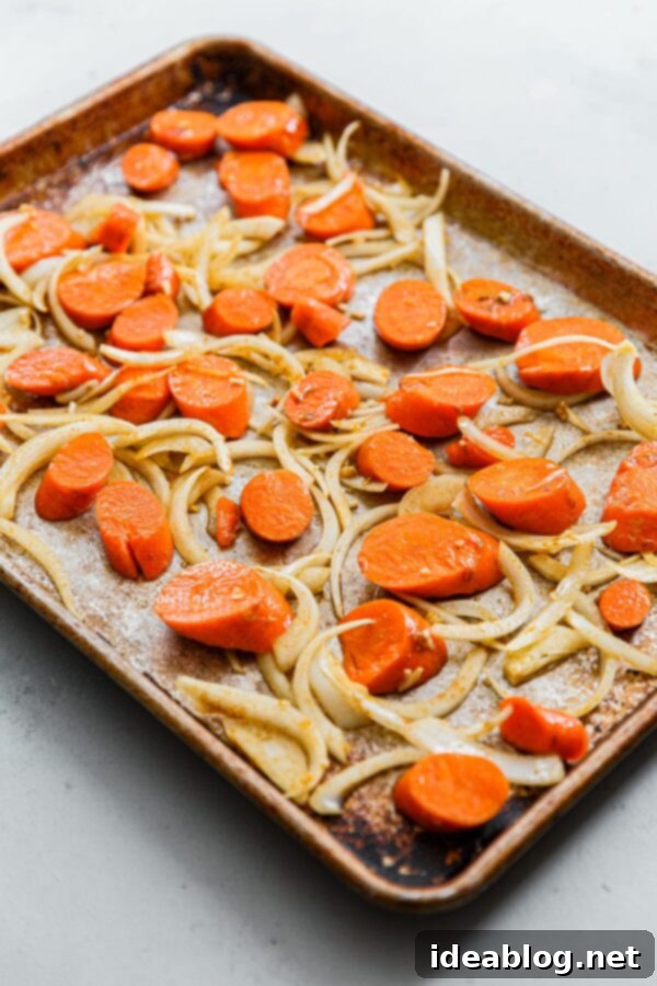 Roasted Golden Carrots with Savory Farro 7 Sliced Carrots and Onions spread in a single layer on a half sheet pan, ready for roasting.