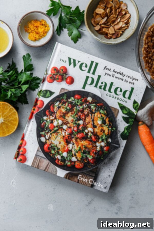 Roasted Golden Carrots with Savory Farro 8 The Well Plated Cookbook open with recipe ingredients for Golden Carrots and Farro alongside it.